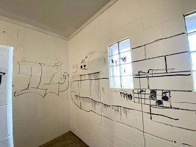 White brick walls are tagged with black graffiti