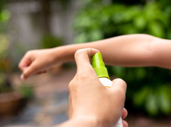 Parent spraying a child's arm with mosquito repellent