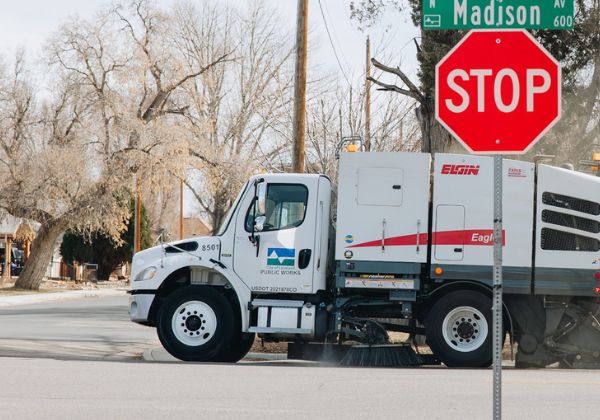 A street sweeping truck approaching a residential intersection.