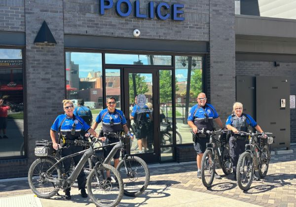 Four police officers on bicycles standing in front of a police station.