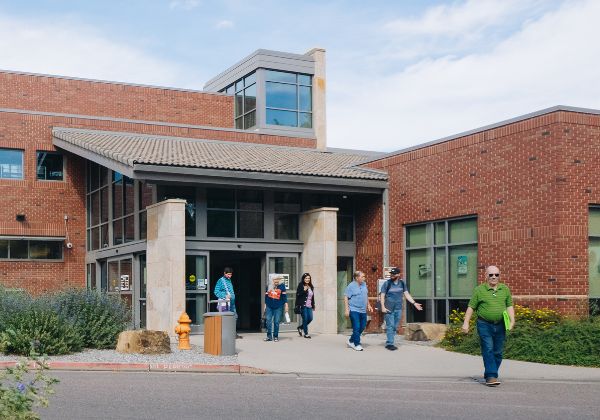 Several people walking in and out of the library.